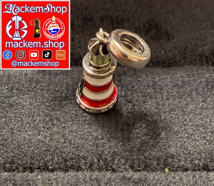 A silver-toned Roker lighthouse charm with red and white enamel stripes, shown on a dark textured surface. A red and white 'MackemShop' logo overlay is in the top-left corner.