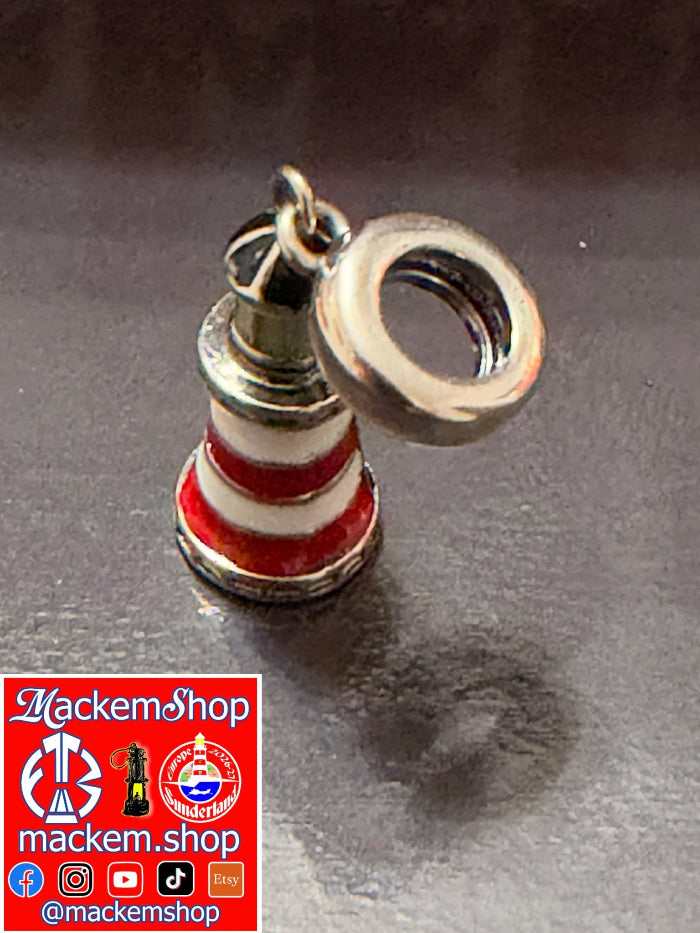 A Roker lighthouse charm with red and white stripes and a silver-toned cap, shown on a dark reflective surface. A red and white 'MackemShop' logo overlay is in the bottom-left corner.