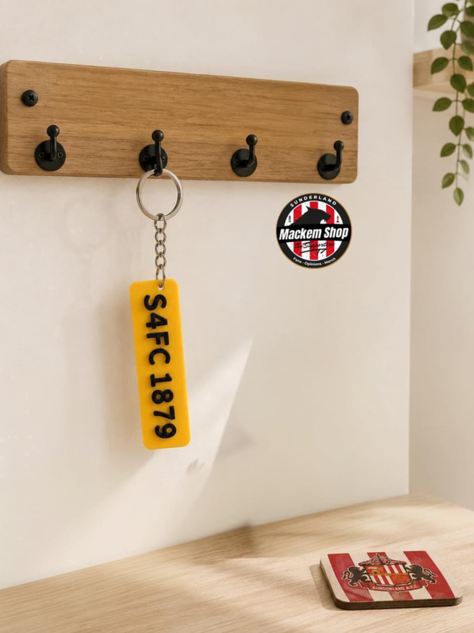 Wooden wall hook with a keychain and coaster on a light wooden surface.