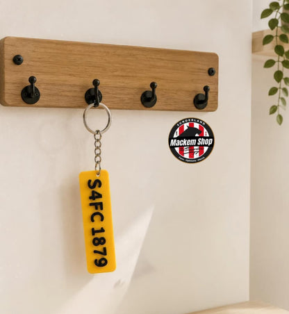 Wooden wall hook with a keychain and coaster on a light wooden surface.