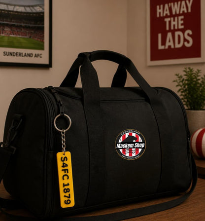 Black duffel bag with a badge and keychain on a wooden surface, with a sports-themed background.