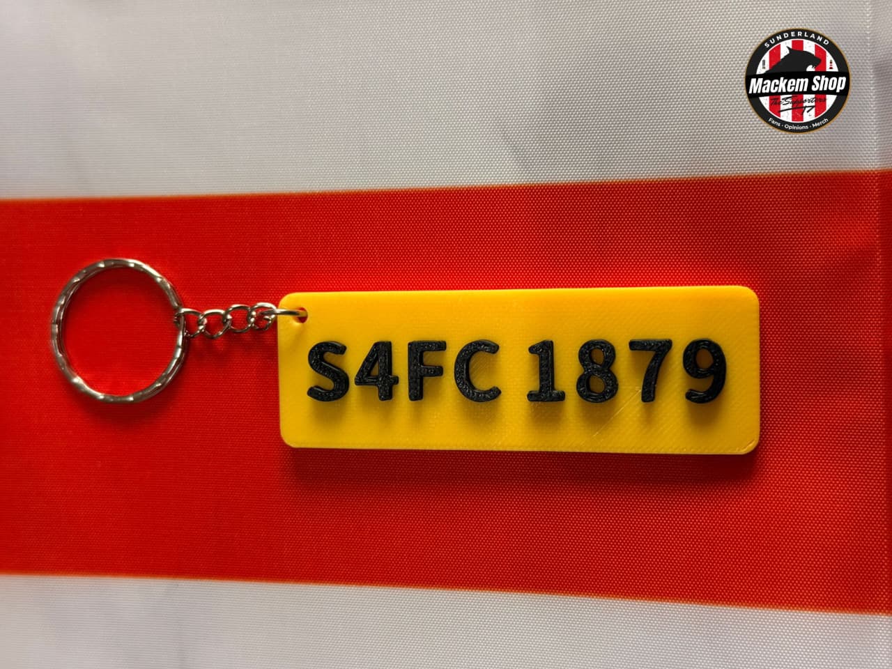 Yellow keychain with black text 'S4FC 1879' on a red and gray background