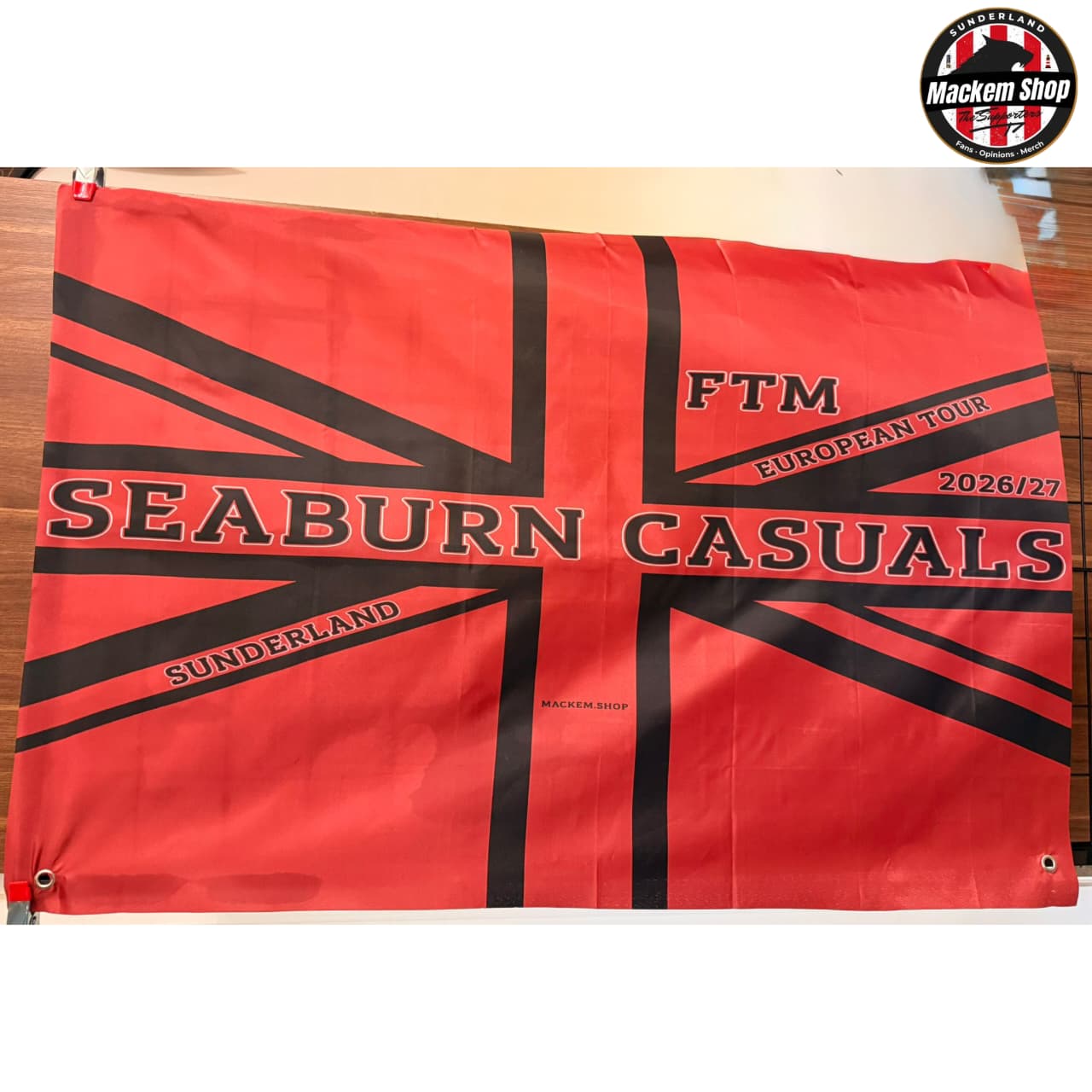 Red and black flag with 'Seaburn Casuals' and 'FTM European Tour' text on a wooden surface.
