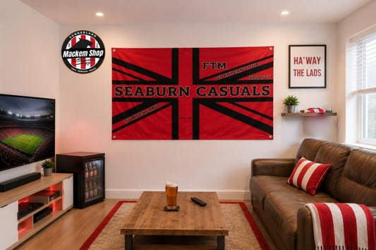A large red and black Seaburn Casuals FTM flag hangs on a white wall in a modern living room setting with a brown leather sofa, wooden coffee table, and a television.