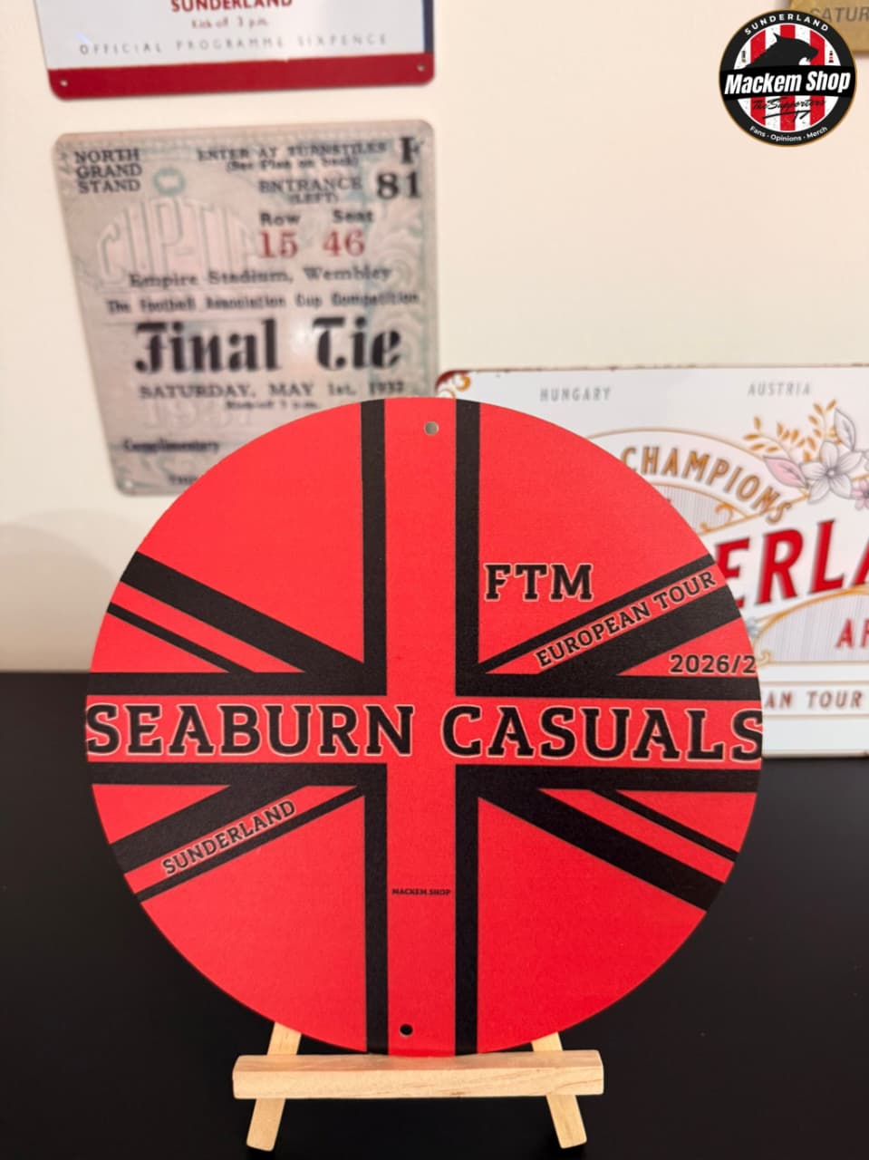 Circular metal sign with 'Seaburn Casuals' text on a stand, with vintage-style posters in the background by MackemShop.