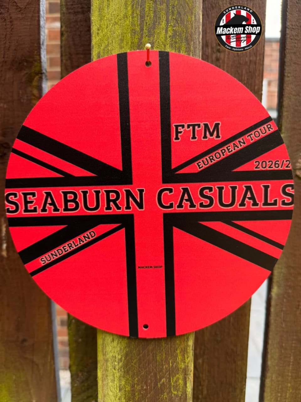Circular metal sign with red and black design featuring 'Seaburn Casuals' and 'FTM European Tour' text, attached to a wooden post by MackemShop.