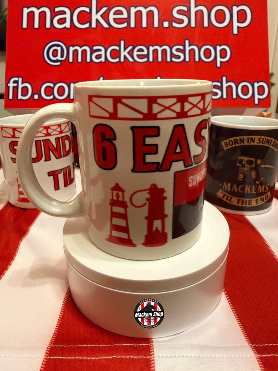 Mackem's branded mug with a red and white design on a red and white checkered tablecloth.