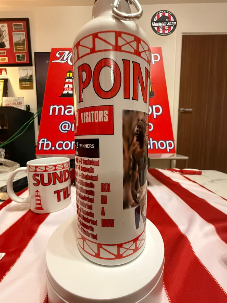 White water bottle with red text on a table with a red and white checkered tablecloth.