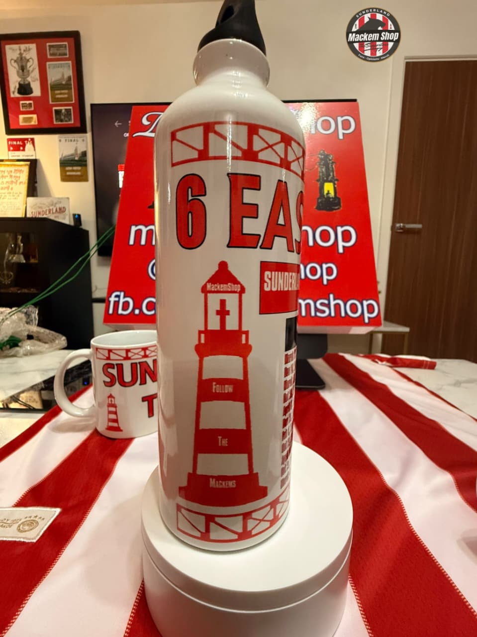 White bottle with red text and graphics on a red and white striped tablecloth.
