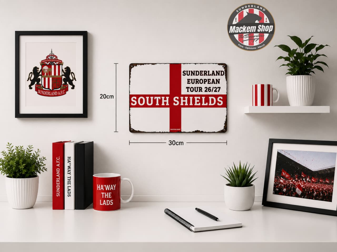 A styled room scene showing a framed Sunderland football-themed wall sign centered on a white wall, with dimension labels reading 20cm and 30cm. The sign has a distressed white background, a bold red cross, and red text reading 'SUNDERLAND EUROPEAN TOUR 26/27 SOUTH SHIELDS.