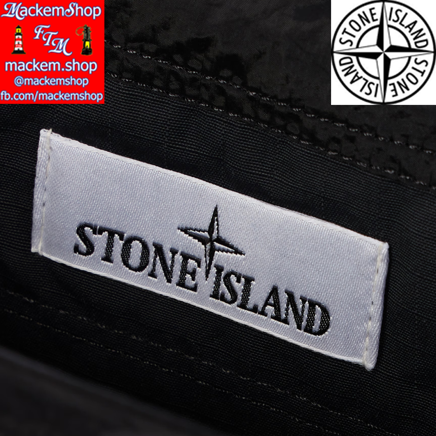 Close-up of Stone Island label on a black background with brand logos and text.
