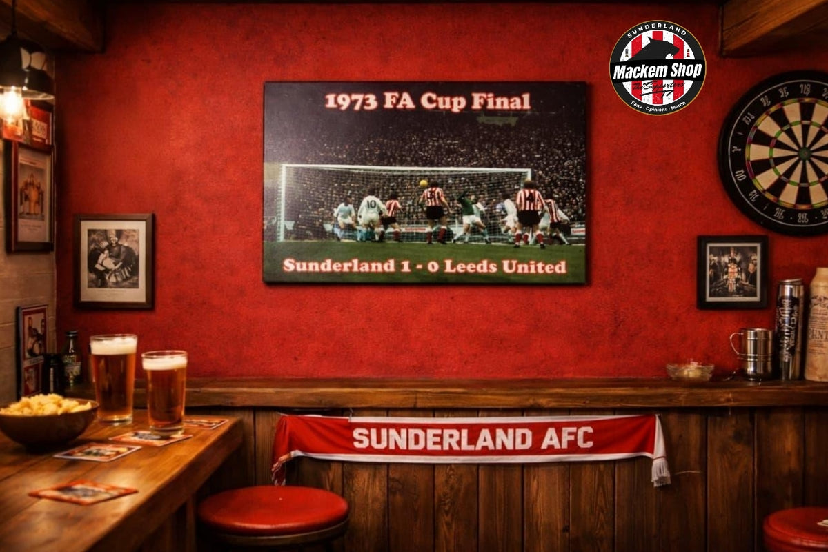 A framed 1973 FA Cup Final Sunderland 1-0 Leeds United sports print hanging on a textured red wall in a pub setting, with a Sunderland AFC banner on the counter below and a Mackent Shop logo in the top right corner.
