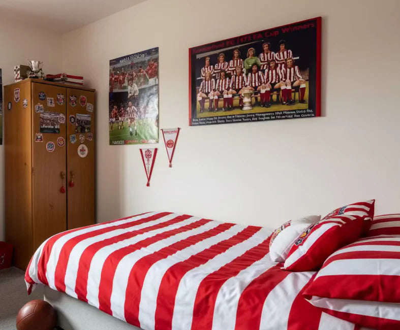 Bedroom with red and white striped bedding, sports-themed posters on the wall.