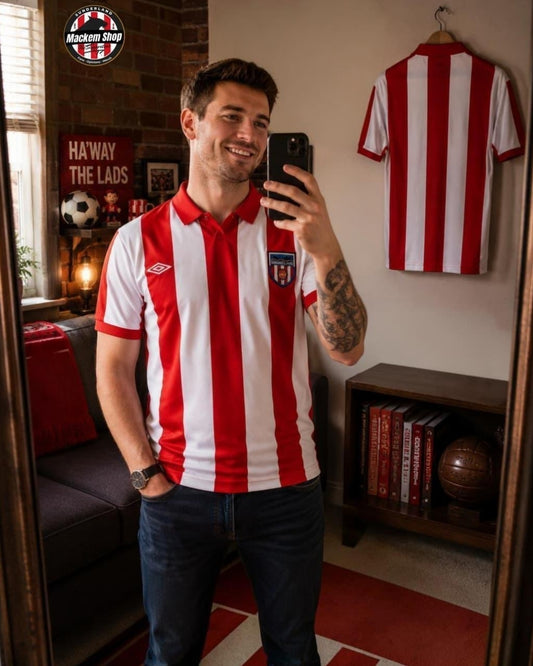 Man wearing a red and white striped shirt taking a selfie in a room with sports memorabilia.