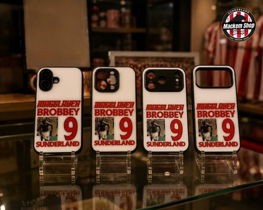 Four white phone cases featuring a red and black 'Maggslayer Brobbey 9 Sunderland' design, displayed on clear acrylic stands on a glass counter inside a store.