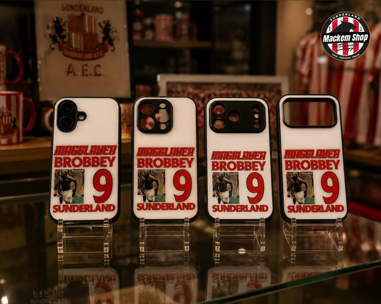 Four phone cases with 'Muggs Over Brobbey' text and number on a stand.