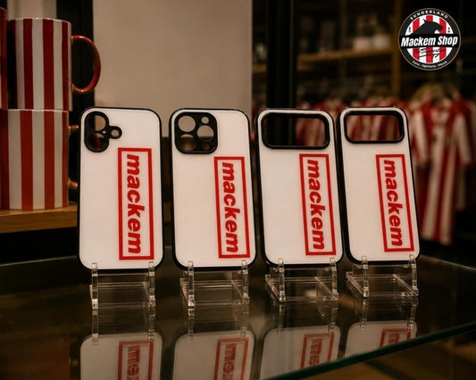 Four white iPhone cases with red 'mackem' logos displayed on clear stands on a glass table, with a red-and-white striped mug in the background and a circular 'MackemShop' logo in the top right.