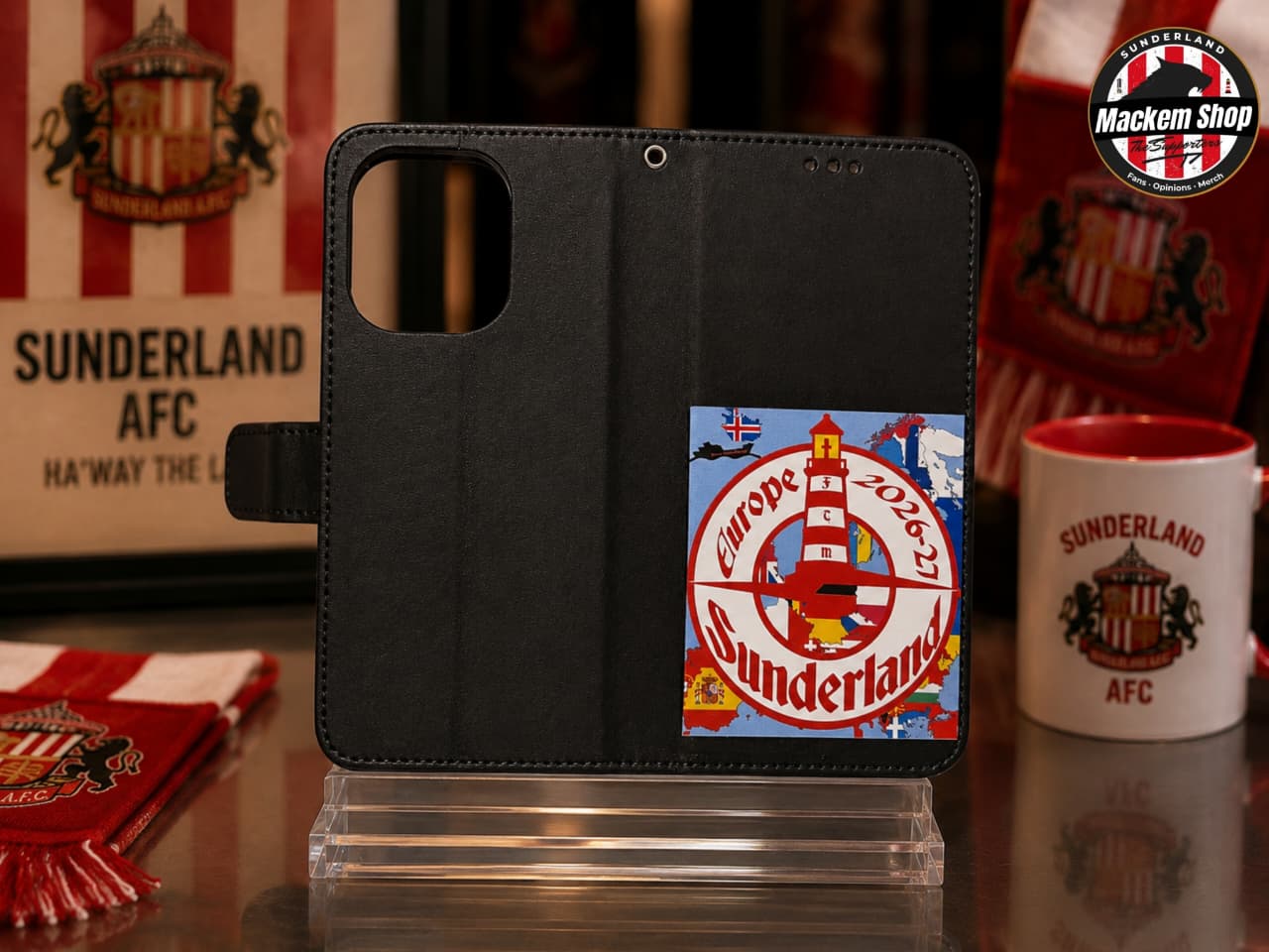 Black folio iphone case with a Sunderland AFC graphic patch, displayed on a clear stand with Sunderland themed items in the background.