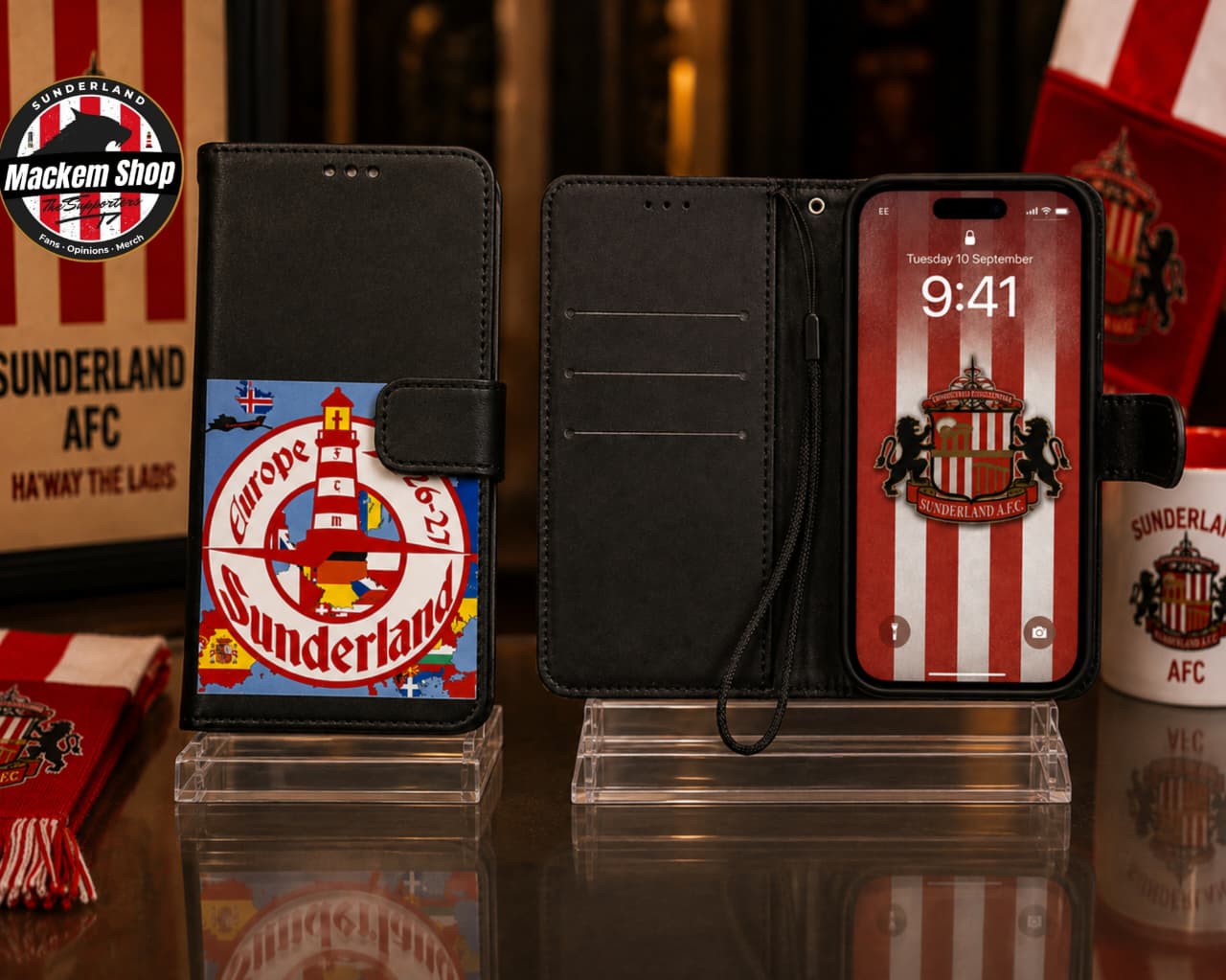 Black folio iphone case with Sunderland AFC branding, shown closed and open on clear display stands. The closed case features a colorful Sunderland AFC crest graphic on the front pocket, and the open case shows a black interior with card slots and a wrist strap.