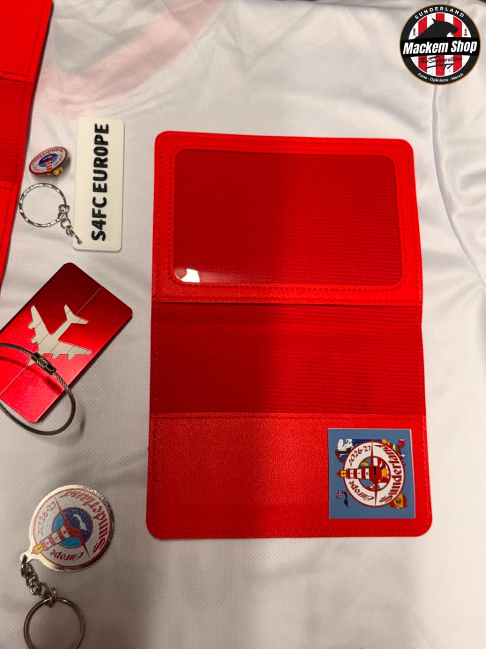 A red foldable passport holder with a clear ID window.