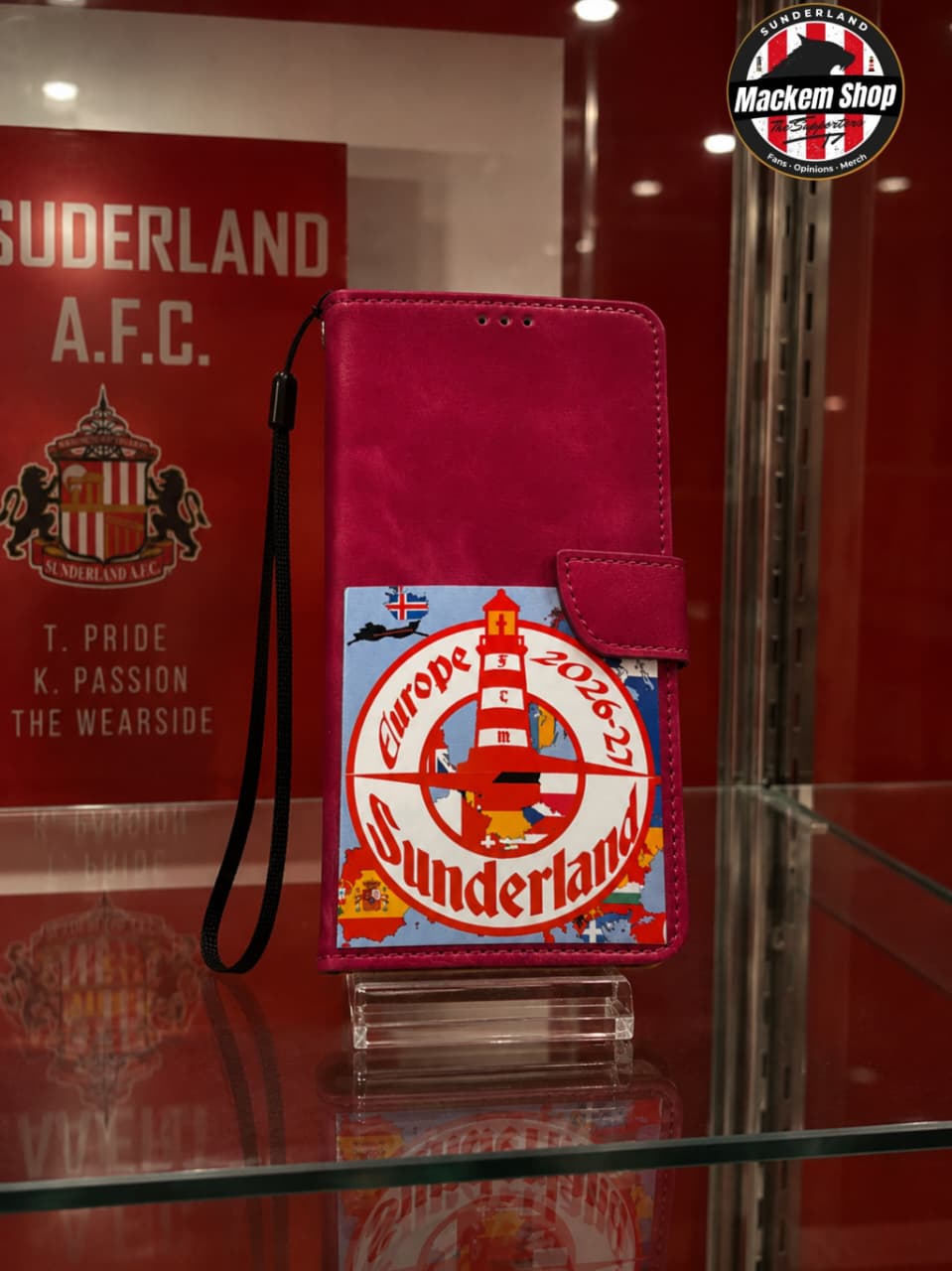 A magenta pink folio phone case with a Sunderland A.F.C. crest patch, displayed on a glass stand inside a shop.