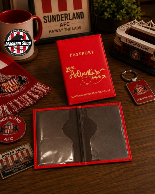 A red Sunderland AFC passport holder set displayed on a wooden table, including a red passport-style holder, a matching red scarf, a mug, a small stadium model, and a keychain, all branded with Sunderland AFC.