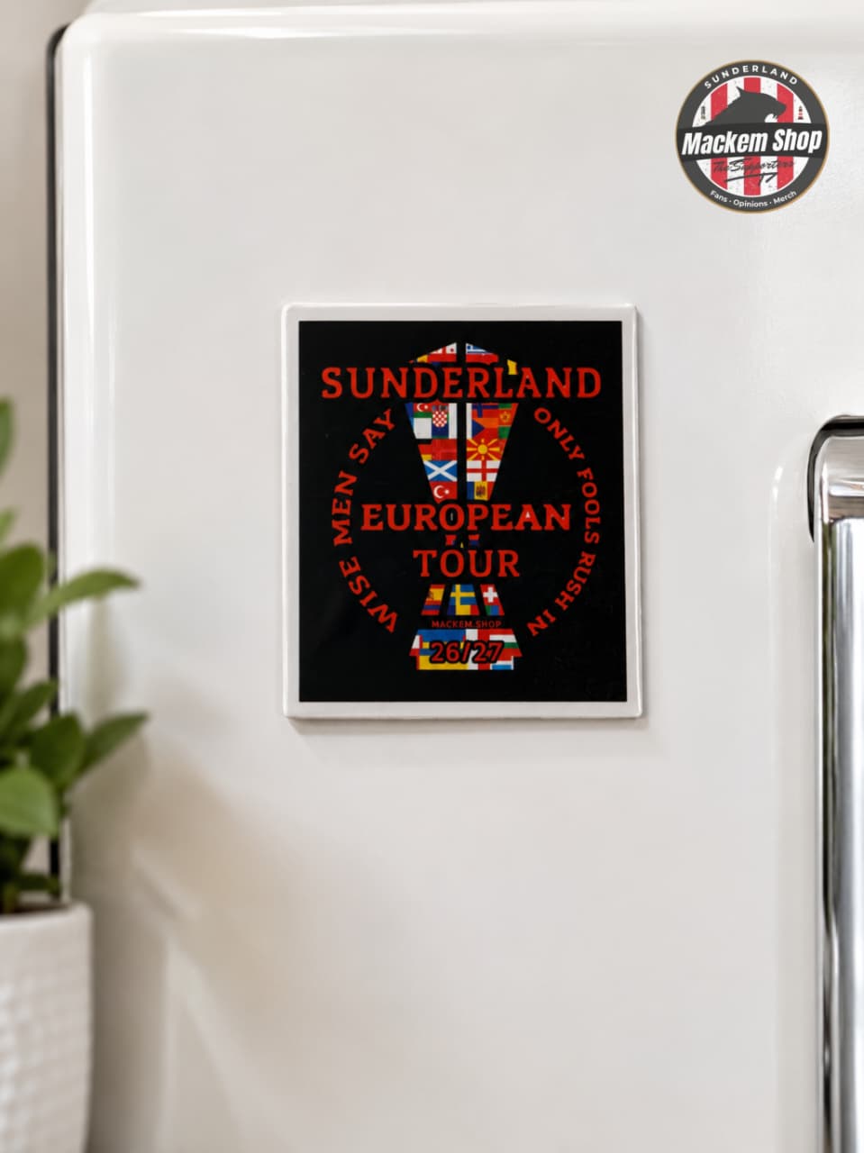 Fridge with a decorative magnet featuring text and flags on a white refrigerator.