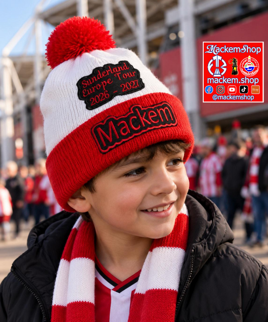 A young boy wearing a red and white knit beanie with a pom-pom and a matching red and white striped scarf, standing in a stadium crowd. The beanie features a black patch reading 'Sunderland Europe Tour 2026-2027' and 'Mackem'.