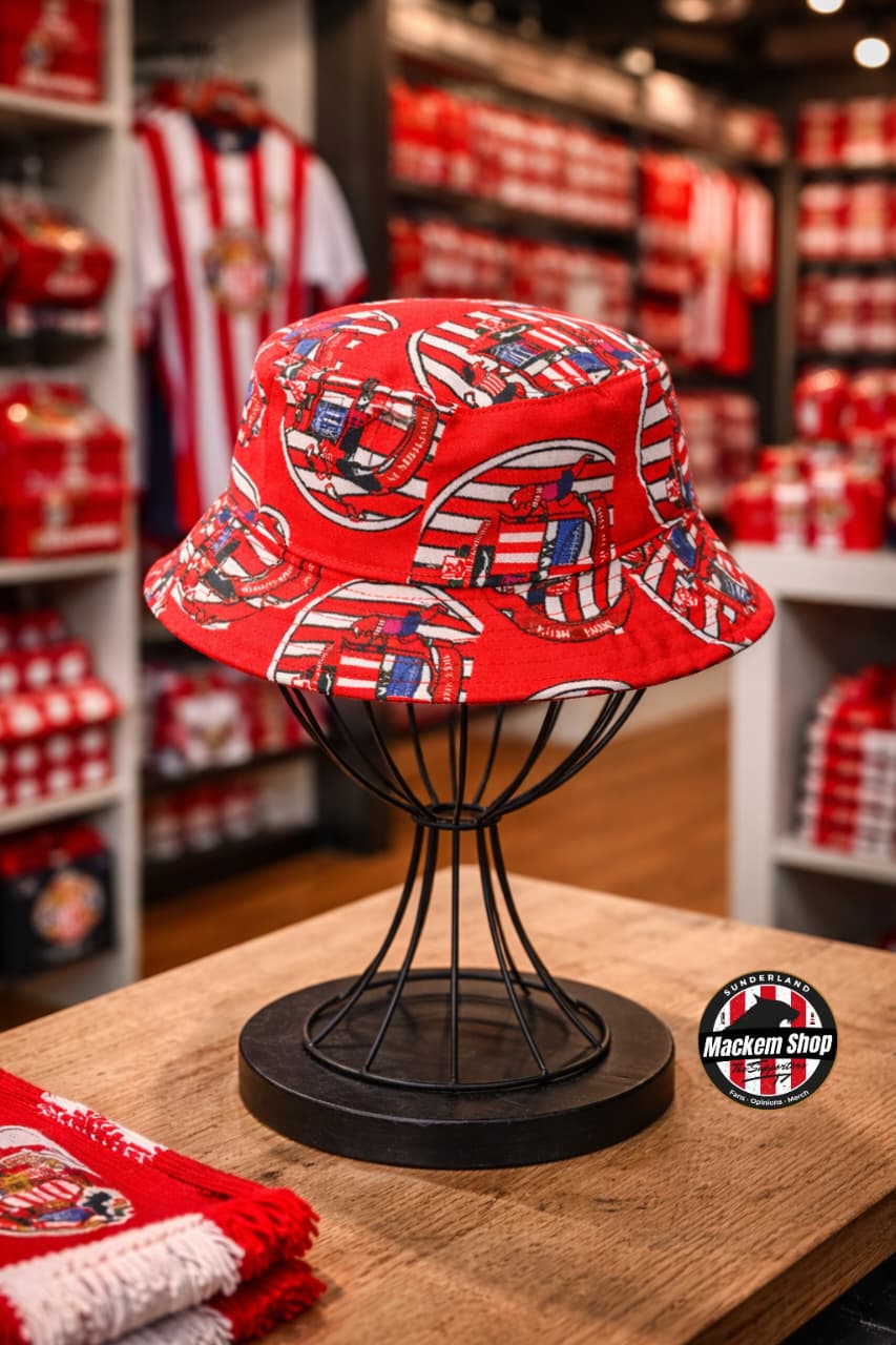 Red patterned bucket hat on a black stand in a store setting with sports merchandise.