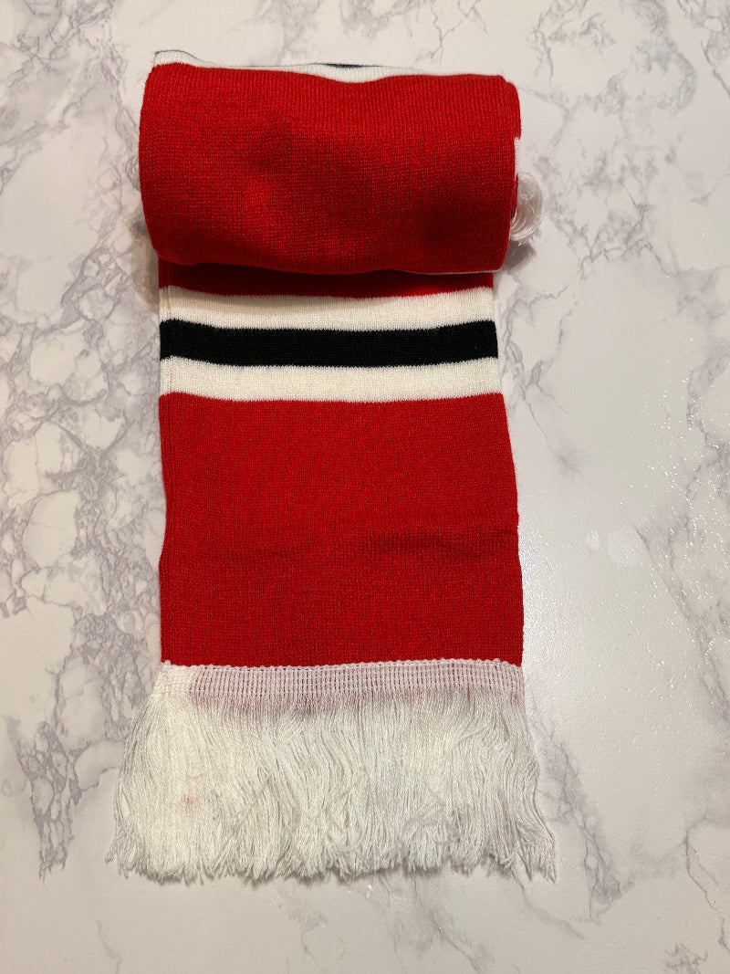 Folded red scarf with white and black stripes on a marble surface