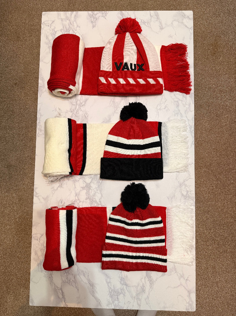 Three scarves with pom-poms on a marble surface