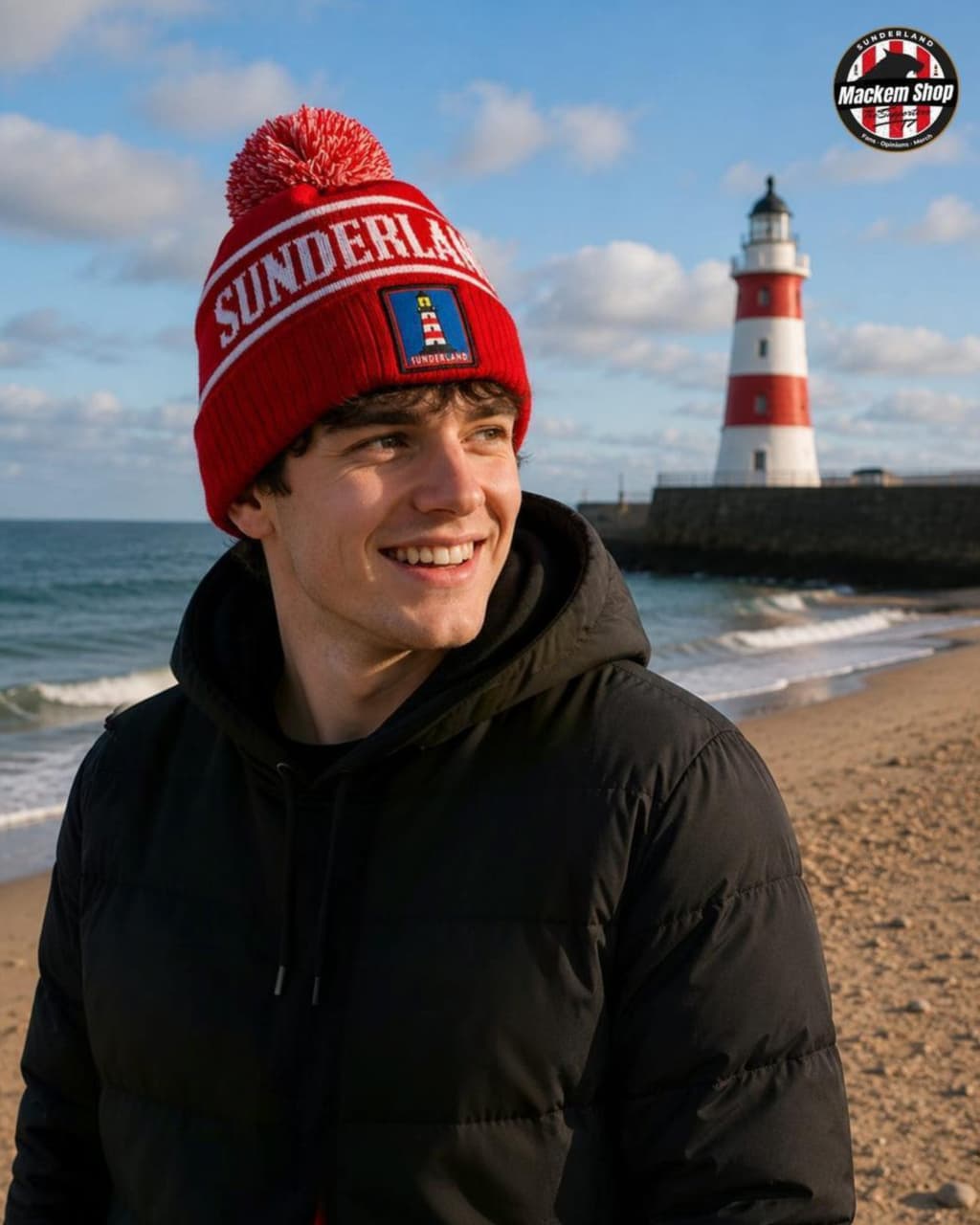 Person wearing a red 'Sunderland' beanie with a lighthouse in the background on a beach.