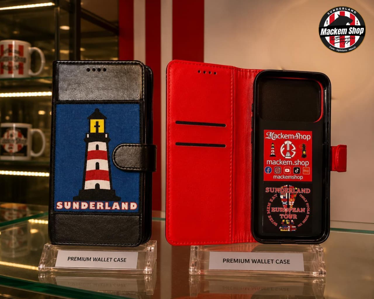 Two premium wallet phone cases displayed on clear stands in a retail setting. The left case is black with a blue front panel featuring a red-and-white lighthouse and the word 'SUNDERLAND.