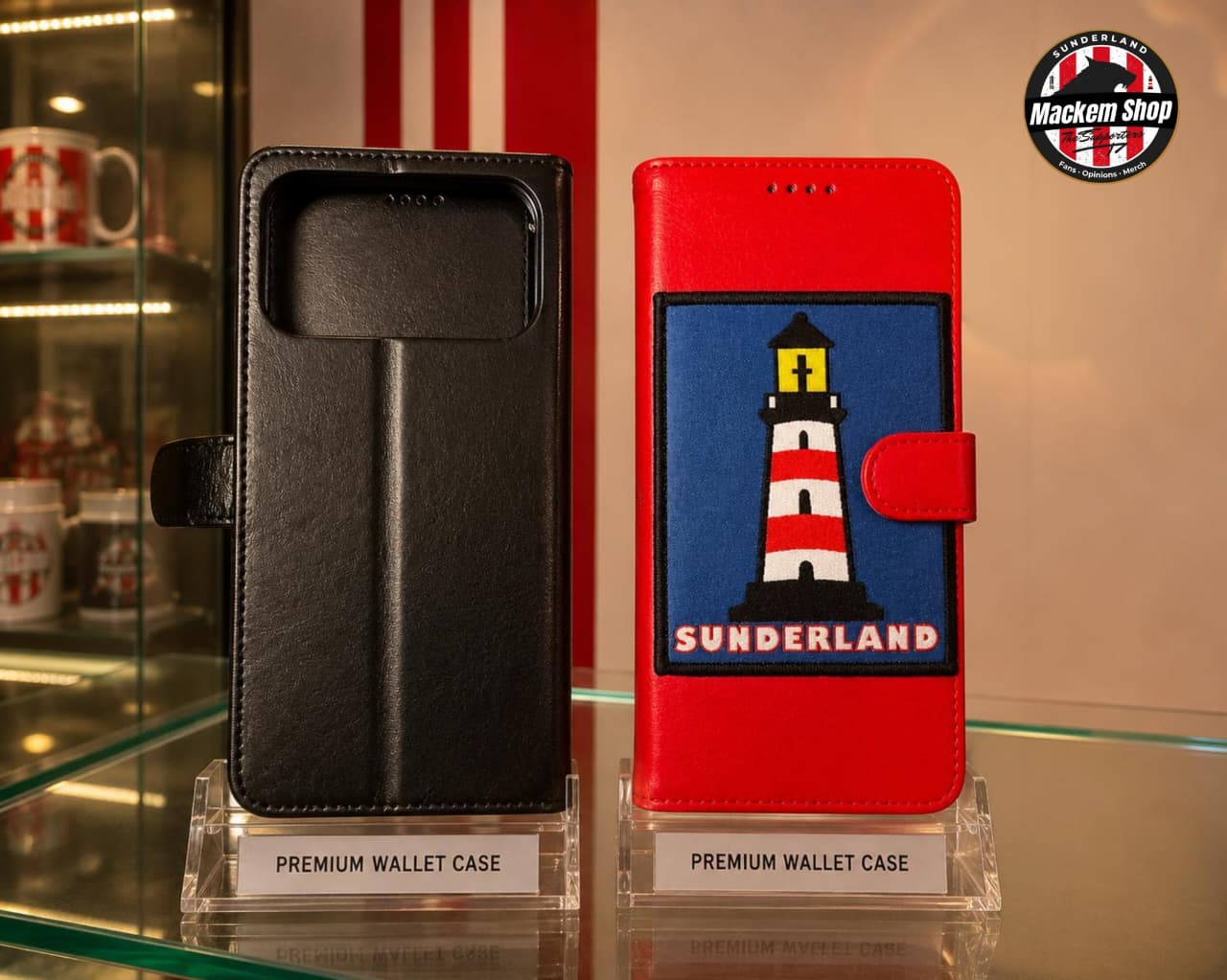 Two premium wallet phone cases displayed on clear acrylic stands on a glass shelf. The left case is black faux leather, and the right case is red with a large embroidered patch featuring a lighthouse and the text 'SUNDERLAND'.