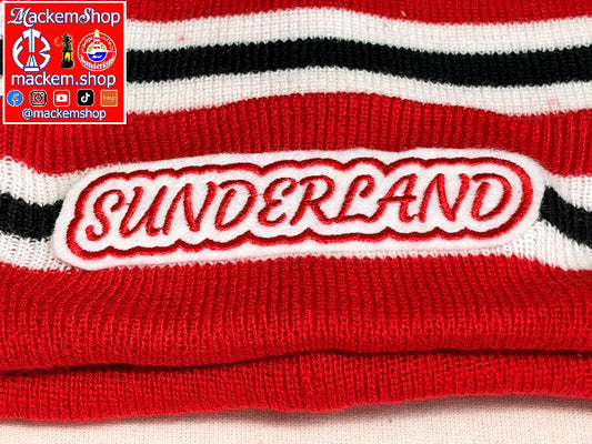 Close-up of a red knit beanie with black and white stripes and a large embroidered 'SUNDERLAND' patch on the front. A Mackem Shop logo overlay is visible in the top-left corner.