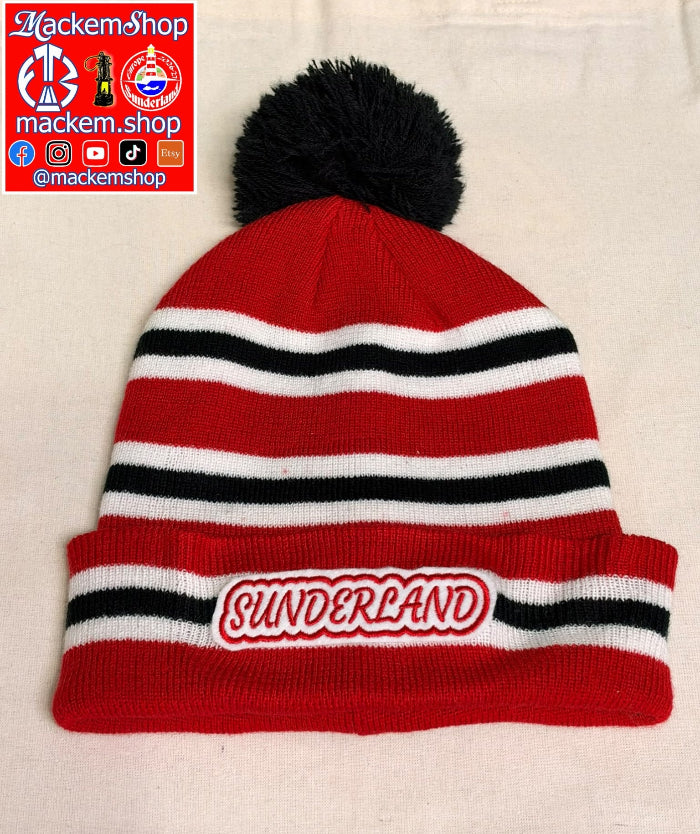 A red, white, and black striped knit beanie with a black pom-pom on top. The front cuff features a white patch with the word 'SUNDERLAND' in red outlined lettering.