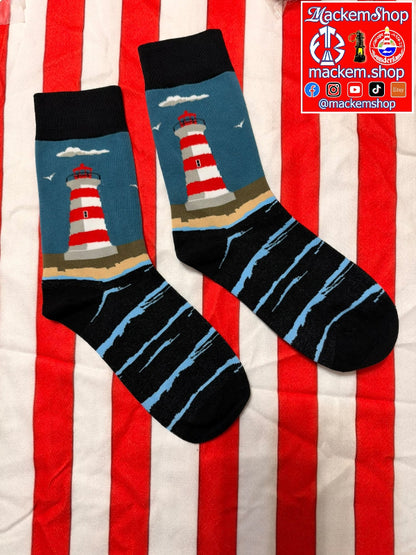 A pair of crew socks laid flat on a red and white striped fabric background. The socks have black cuffs and toes, light blue and black striped lower sections, and a printed lighthouse design on the upper portion, and a MackemShop logo on top right corner.
