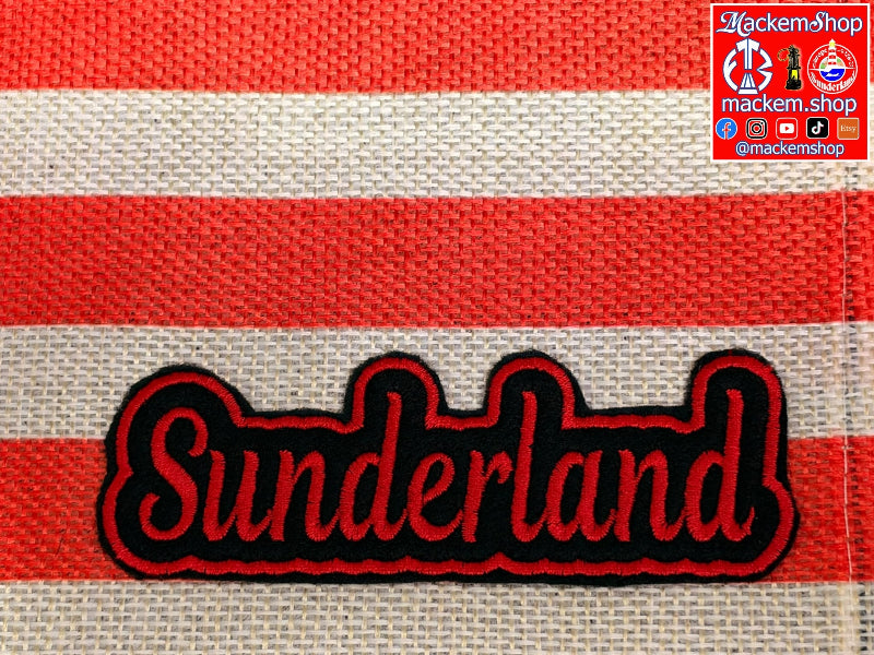 A close-up of a woven textile with horizontal red and off-white stripes and a large, embroidered patch reading "Sunderland" in red with a black outline. A small "MackemShop" logo appears in the top-right corner.