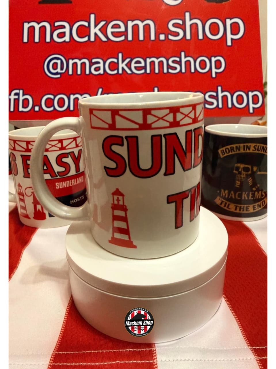 White mug with red text and lighthouse design on a red background with 'mackem.shop' branding.