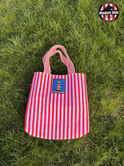 Red and white striped Tote bag with Sunderland Lighthouse logo put on grass, featuring 'Mackem Shop' logo.