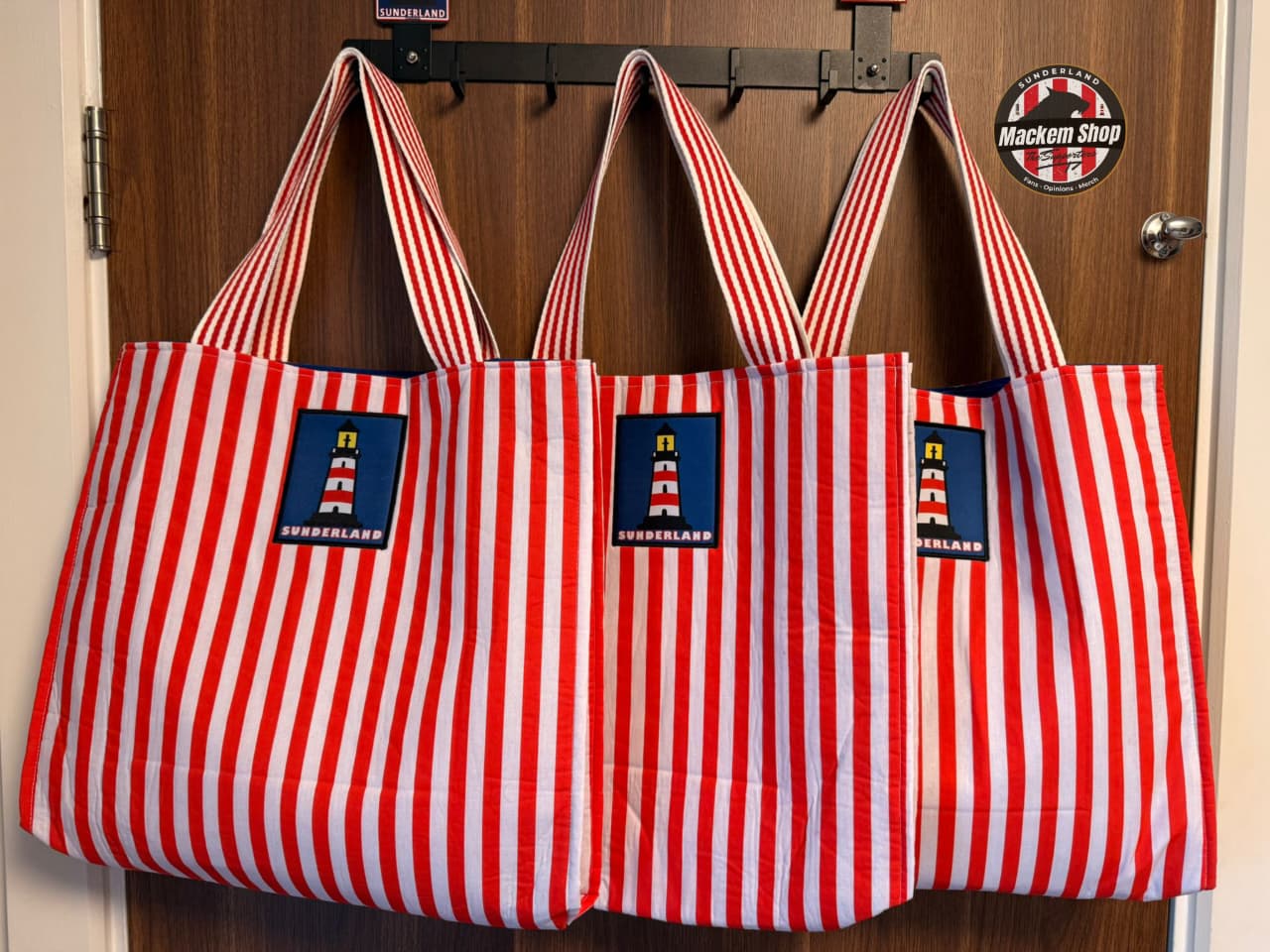 Three Sunderland tote bags displayed together on hooks with front logo visible