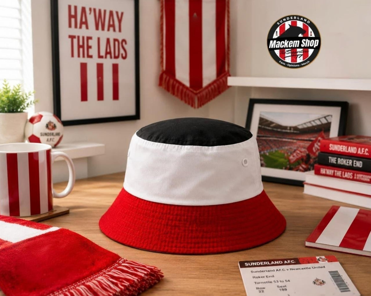 A red, white, and black bucket hat styled on a wooden desk.