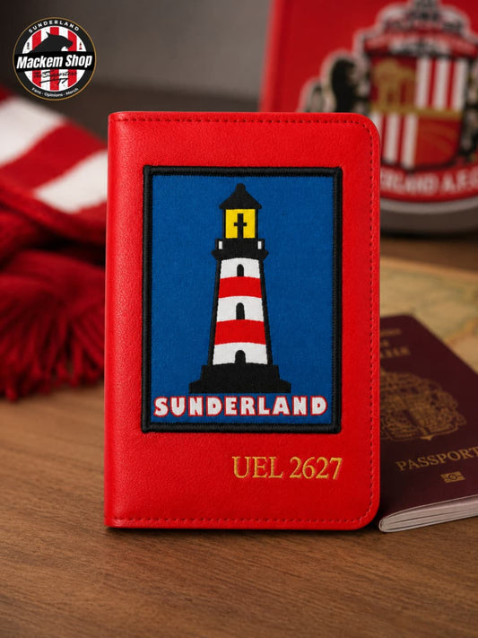 A red faux-leather passport cover featuring a Sunderland football club crest patch with a lighthouse on a blue background, and the text 'SUNDERLAND' and 'UEL 2627' in gold. The cover is displayed on a wooden surface with a blurred Sunderland scarf, a red Sunderland jersey, and a passport in the background.