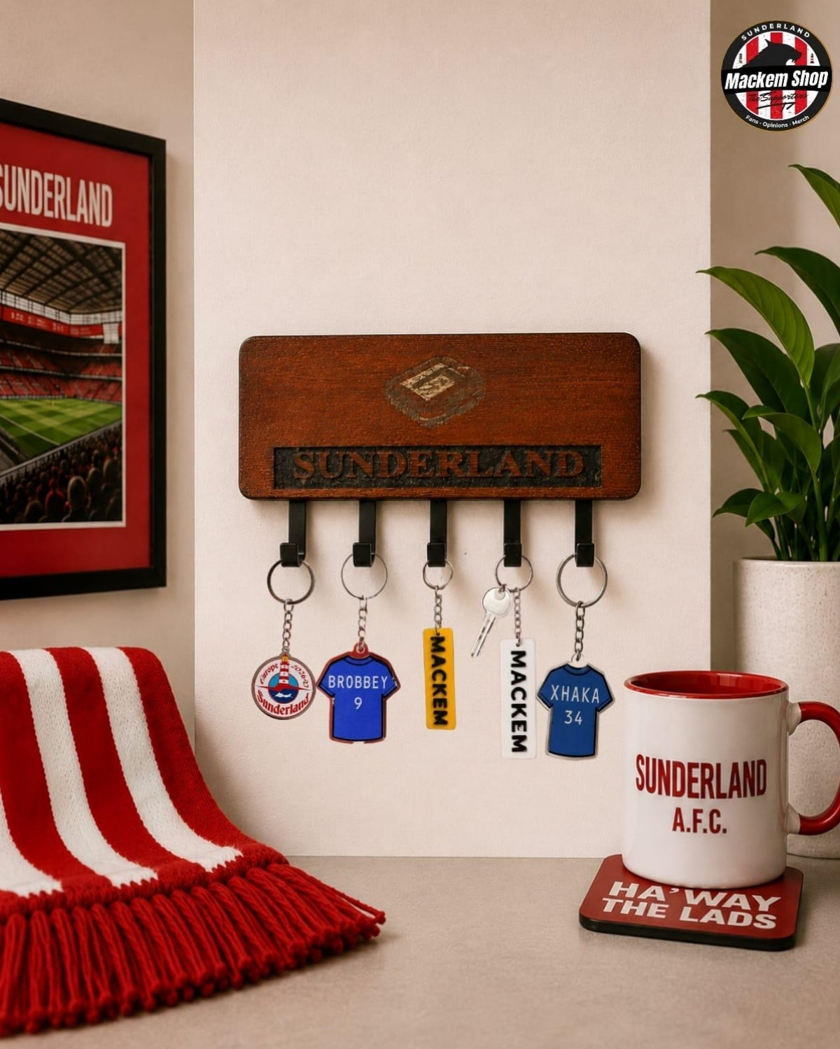 A wooden Sunderland AFC key holder mounted on a beige wall, holding several keys and small badges. A red-and-white striped scarf hangs on the left.