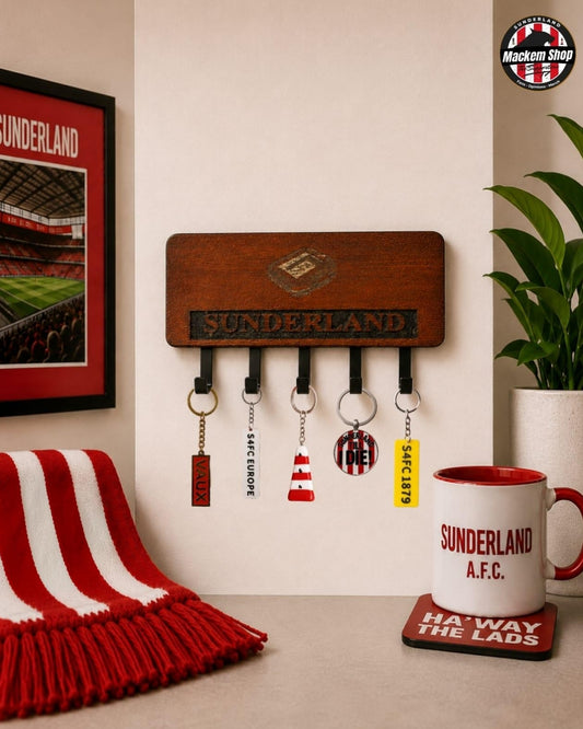 A wooden Sunderland AFC wall key holder with five hanging keys, styled in a home environment with a red and white striped scarf, a framed Sunderland poster, a potted plant, and a Sunderland mug.