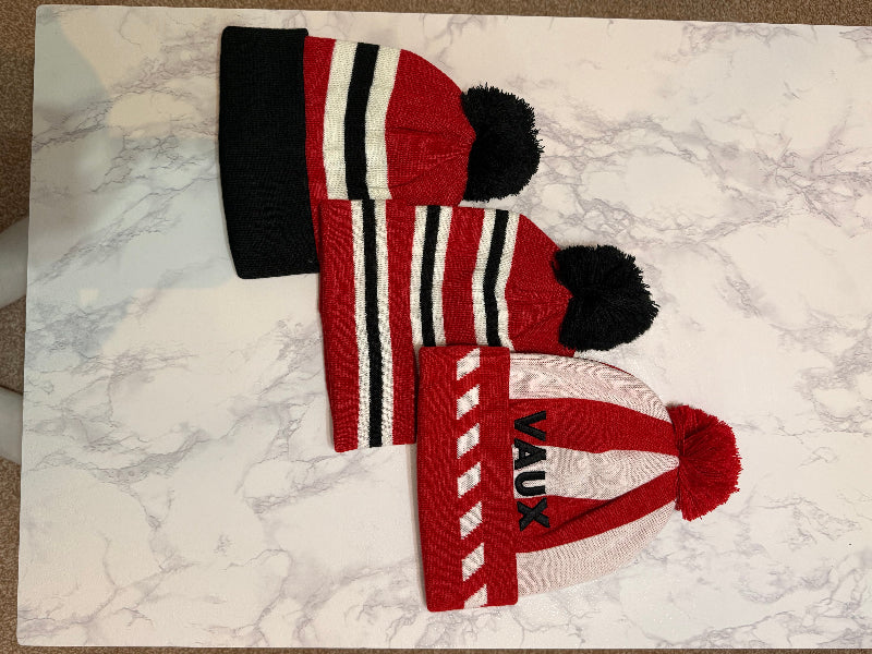Red and black and white knit hat set on a marble surface