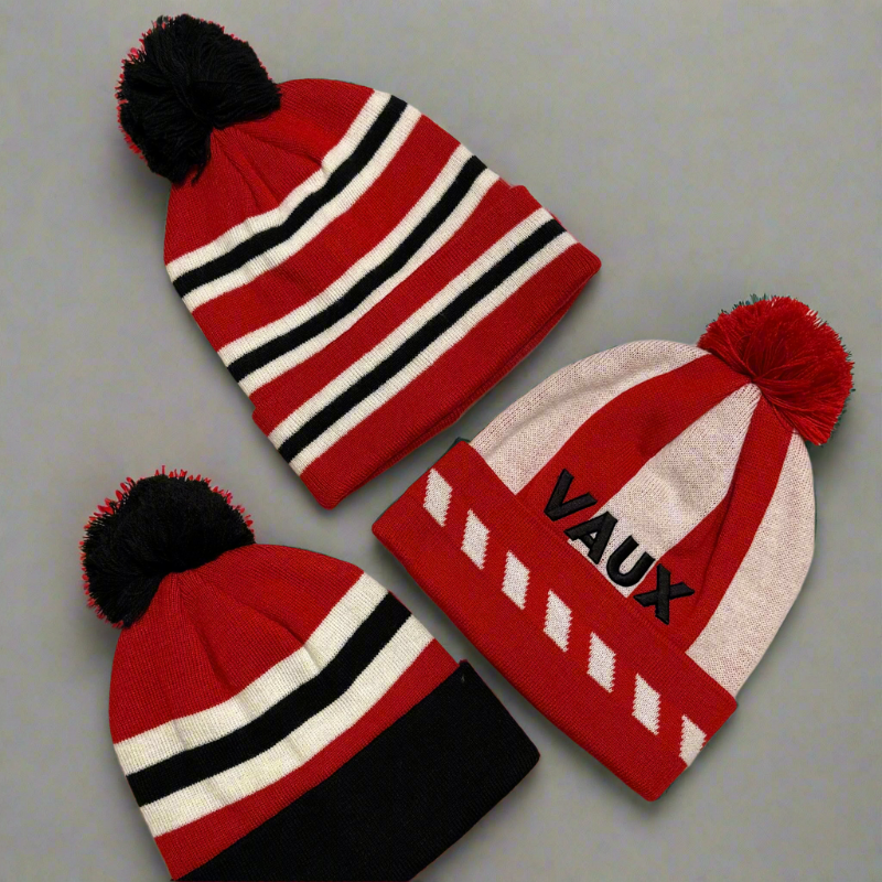 Three red beanies with pom-poms on a gray background