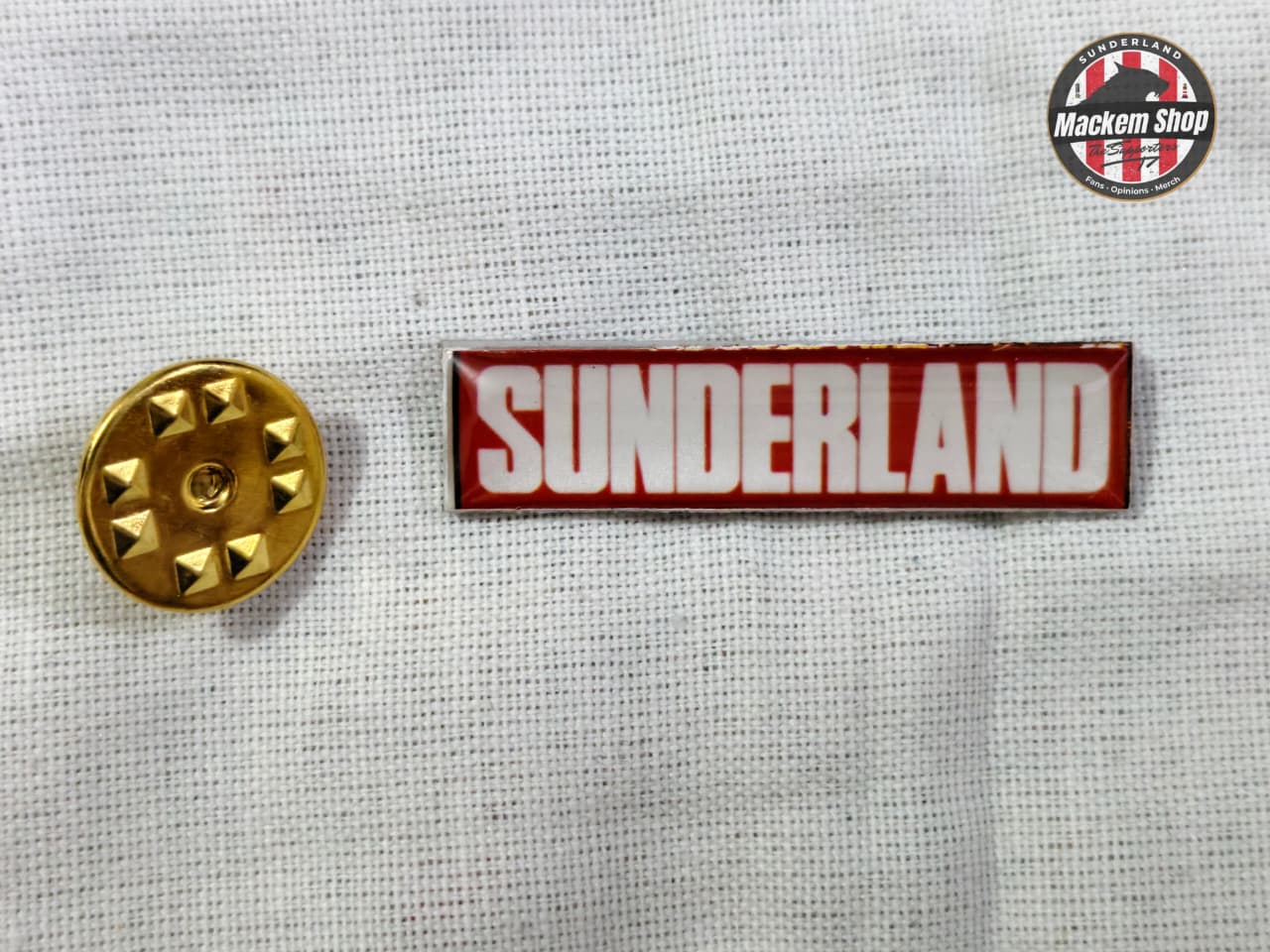 Gold button and 'Sunderland' badge on a textured white background