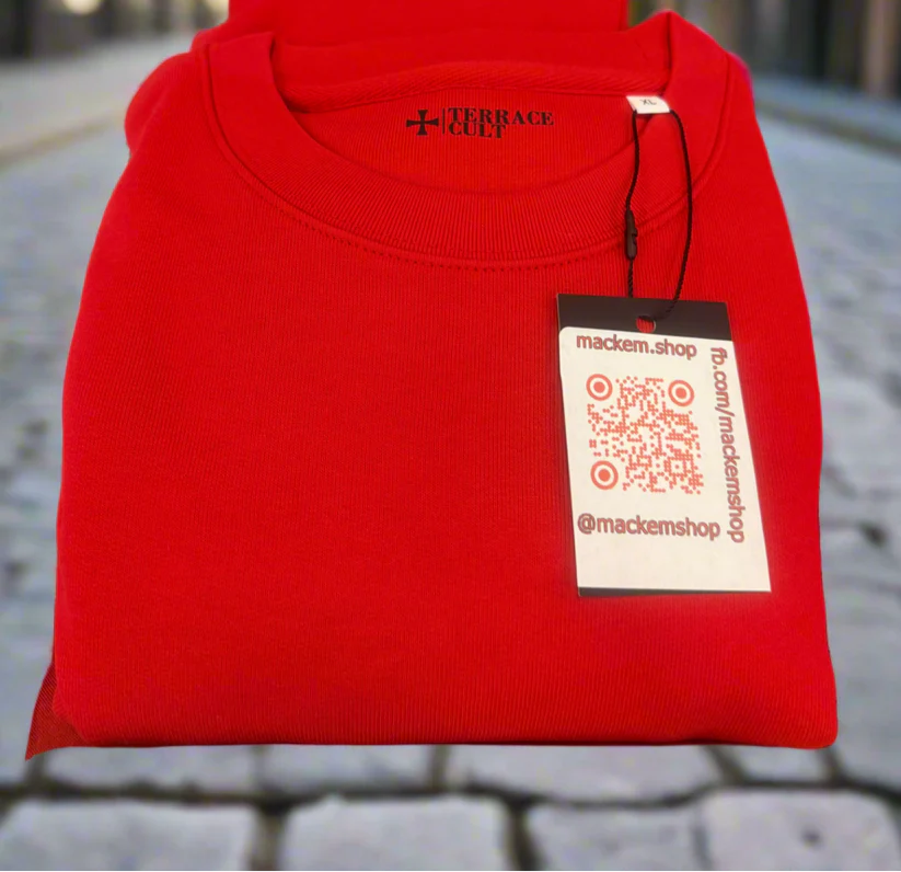 Folded red sweatshirt with Mackem shop brand tag on a blurred background