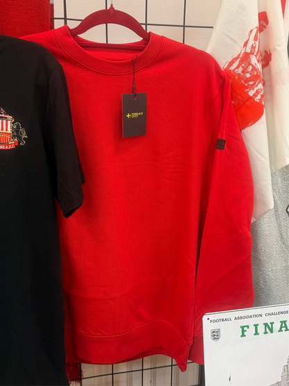 Red sweatshirt with a tag on a hanger against a tiled wall.